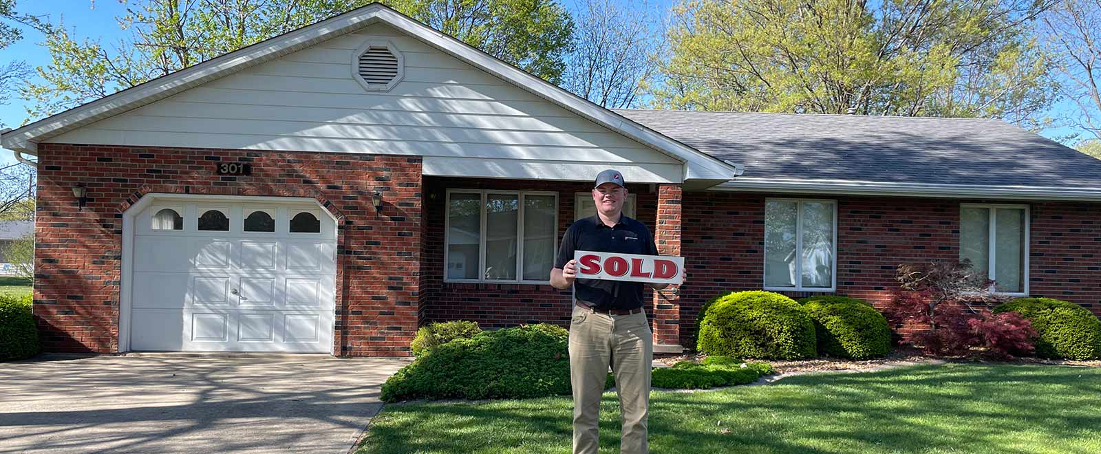 client standing with a Sold sign outside of a residential home